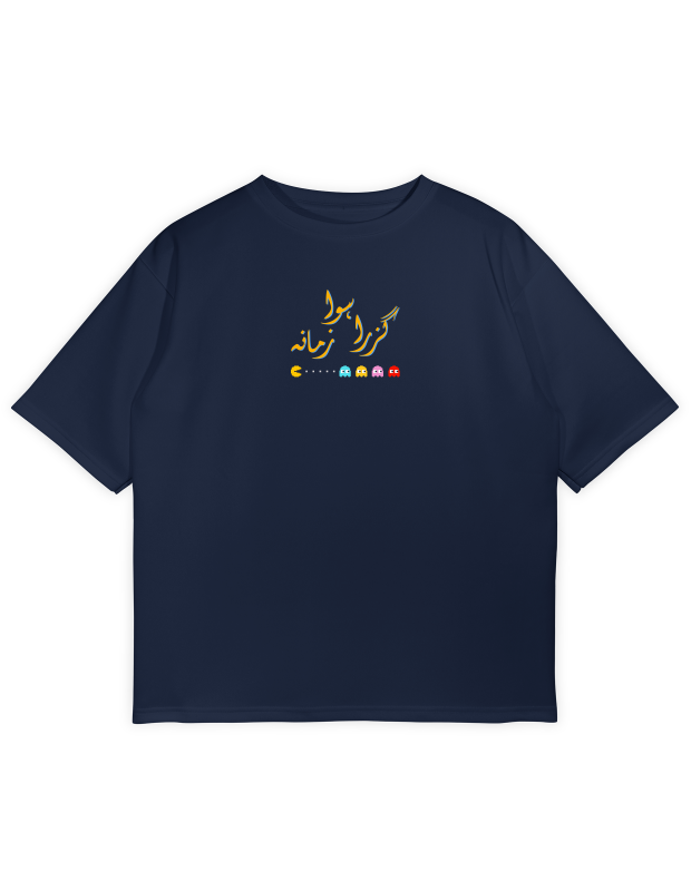 A dark navy blue t-shirt featuring Urdu calligraphy text "Guzra howa Zamana" (meaning 'A time that has passed') in yellow and orange, with a small paper airplane graphic. Below the text are Pac-Man and the four ghosts (Blinky, Pinky, Inky, and Clyde).